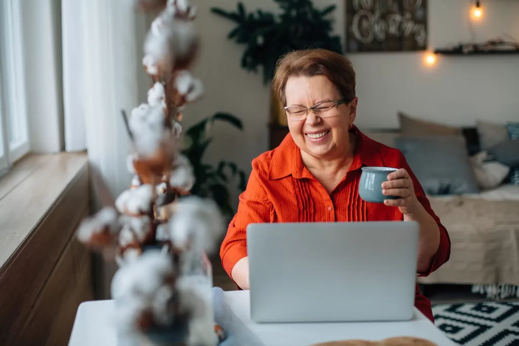 elderly woman laughing and smiling in front of a computer